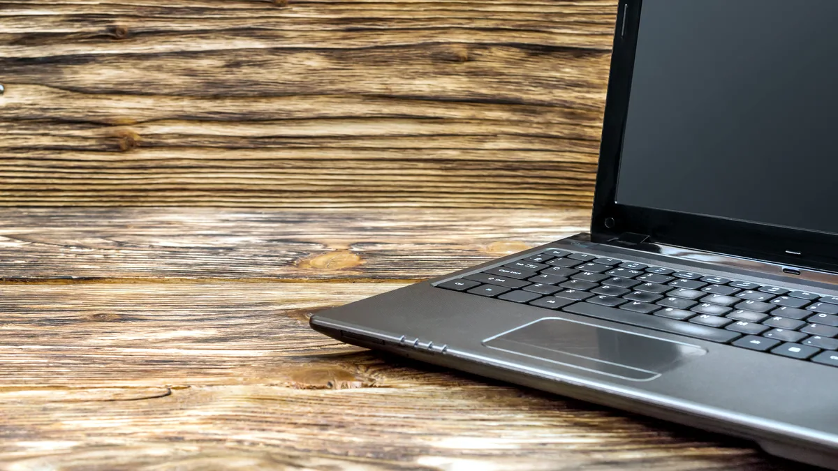 A slim laptop running a Linux desktop on a clean wooden desk.