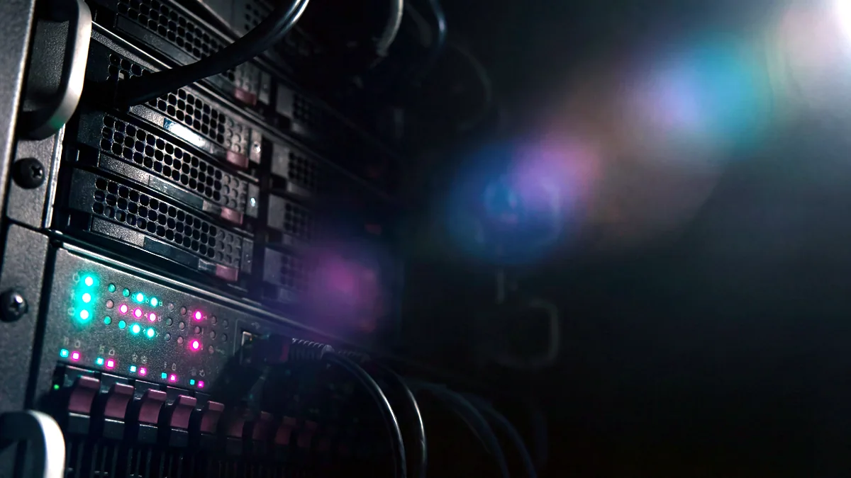 Rows of server hardware with blinking status lights in a dim rack room.